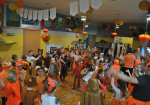 Dzieci i nauczyciele wspólnie bawią się na balu jesieni. Uczestnicy balu są poprzebierani w stroje związane z tematyką imprezy. Ujęcie 2