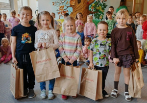Dzieci, które otrzymały w konkursie nagrody pozują do wspólnego zdjęcia. W tle pozostałe dzieci z przedszkola. Ujęcie 2