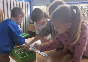 Dzieci budują tor dla robota korzystając ze specjalnych puzzli.