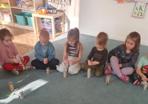 Dzieci siedzą na dywanie. Przed dziećmi stoją wykonane prace - kotki z tekturowych rolek po papierze toaletowym. Ujęcie 4