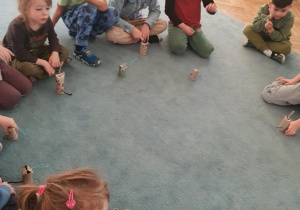 Dzieci siedzą na dywanie. Przed dziećmi stoją wykonane prace - kotki z tekturowych rolek po papierze toaletowym. Ujęcie 5