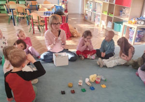 Dzieci i nauczycielka siedzą na dywanie.