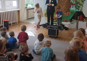 Iluzjonista w trakcie występu. Ujęcie 3. Artyście towarzyszy dwoje dzieci.