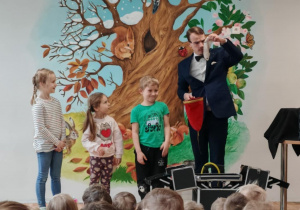 Iluzjonista w trakcie występu. Ujęcie 5. Artyście towarzyszy troje dzieci.