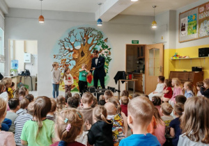 Iluzjonista w trakcie występu. Ujęcie 7. Artyście towarzyszy troje dzieci.