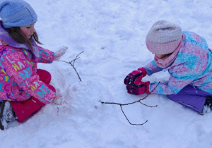 Grupa dzieci w zimowych strojach biega i bawi się w pełnym śniegu ogrodzie w przedszkolu. Ujęcie 2