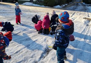Grupa dzieci zbiera kawałki lodu z parkingu. Ujęcie 1