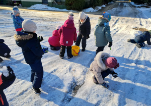 Grupa dzieci zbiera kawałki lodu z parkingu. Ujęcie 2