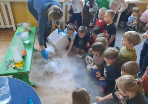 Dzieci obserwują nauczycielkę wykonującą eksperymenty. Ujęcie 1