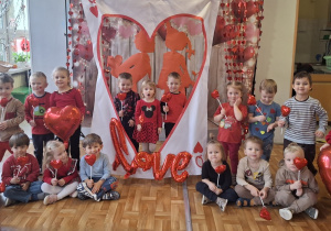 Dzieci pozują do wspólnego zdjęcia z ozdobami walentynkowymi. Zdjęcie częściowo anonimizowane.