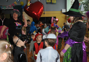 Bal karnawałowy. Dzieci i nauczyciele w przebraniach karnawałowych wspólnie tańczą. Ujęcie 2