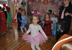 Bal karnawałowy. Dzieci i nauczyciele w przebraniach karnawałowych wspólnie tańczą. Ujęcie 1