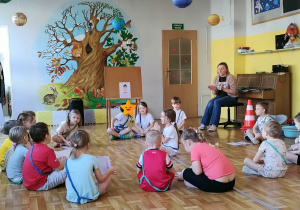 Dzieci i nauczycielka siedzą w kole.