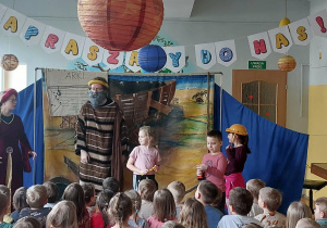 Spektakl w przedszkolu. Na scenie aktorzy w przebraniach i dzieci.