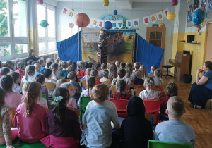 Spektakl w przedszkolu. Na scenie aktor w przebraniu. Dzieci i nauczyciele siedzą na widowni.