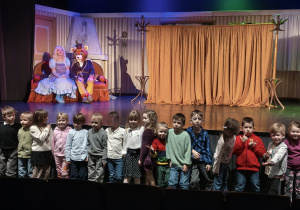 Dzieci pozują do wspólnego zdjęcia na tle sceny i aktorów. Grupa 3