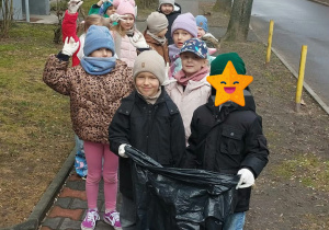 Dzieci pozują do wspólnego zdjęcia w czasie sporzątania terenów zielonych wokół przedszkola. Grupa 3