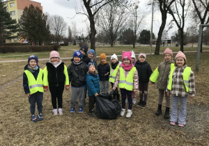Dzieci pozują do wspólnego zdjęcia w czasie sprzątania terenów zielonych. Grupa 5