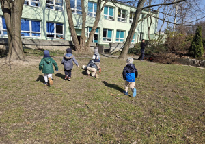 Dzieci z grupy 1 bawią się w ogrodzie przedszkolnym wczesną wiosną. Ujęcie 12. Dzieci biegną za piłką.