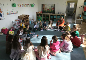 Dzieci i nauczycielka siedzą na dywanie. Grupa 5. Ujęcie 1