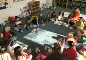 Dzieci i nauczycielka siedzą na dywanie. Grupa 5. Ujęcie 2