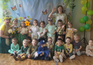 Dzieci i nauczyciele pozują do zdjęcia grupowego na balu wiosny. Grupa 1