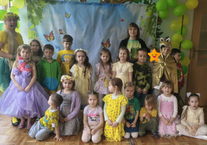 Dzieci i nauczyciele pozują do zdjęcia grupowego na balu wiosny. Grupa 5