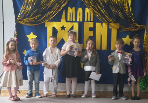 Dzieci z grupy 3 pozują do zdjęcia po występie. Zaprezentowały: pokaz gimnastyki artystycznej, pokaz karate, piosenkę, wiersz, grę na pianinie.