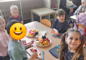 Dzieci z grupy 3 siedzą przy stoliku i przygotowują owoce do "owocowych szaszłyków". Ujęcie 3