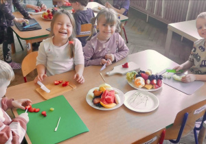 Dzieci z grupy 3 siedzą przy stoliku i przygotowują owoce do "owocowych szaszłyków". Ujęcie 4