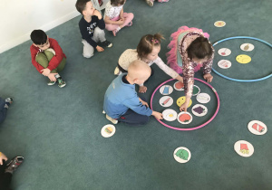 Dzieci siedzą na dywanie, a pomiędzy nimi znajdują się obrazki z żywnością. Ujęcie 2