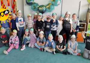 Grupa dzieci pozuje do wspólnego zdjęcia z okazji Dnia Ziemi. Dzieci znajdują się w swojej sali przedszkolnej. Zdjęcie częściowo anonimizowane.