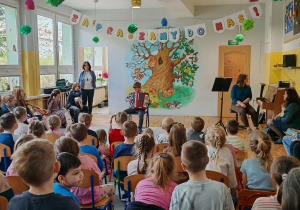 Dziecko gra na instrumencie. Widać dzieci siedzące na scenie. Ujęcie 1