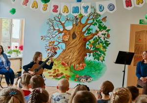 Dziecko gra na instrumencie. Widać dzieci siedzące na scenie. Ujęcie 3