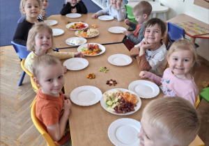 Grupa dzieci siedzi przy stole zastawionym warzywami i owocami. Ujęcie 4