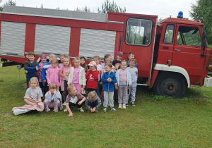 Zabawy i zajęcia w Michałówce. Dzieci pozują do wspólnego zdjęcia na tle wozu strażackiego. Grupa 5