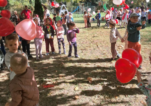 Ogród. Dzieci trzymają patyczki z balonikami w kształcie serc. Grupa 3. Ujęcie 2