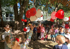 Ogród. Dzieci trzymają patyczki z balonikami w kształcie serc. Grupa 3. Ujęcie 3